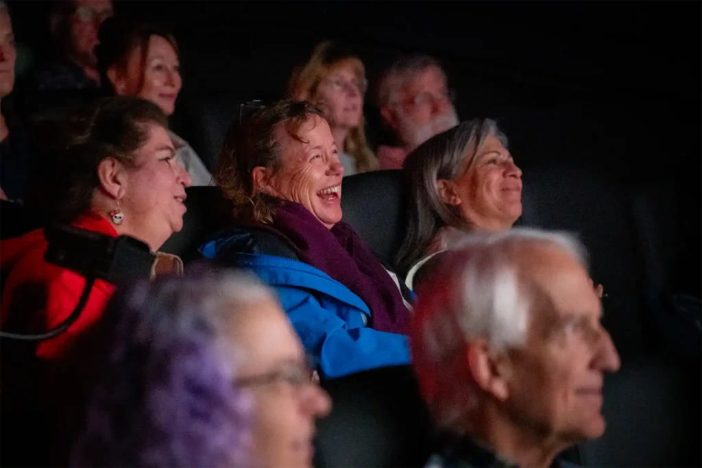 Audience in a movie theater laughing.